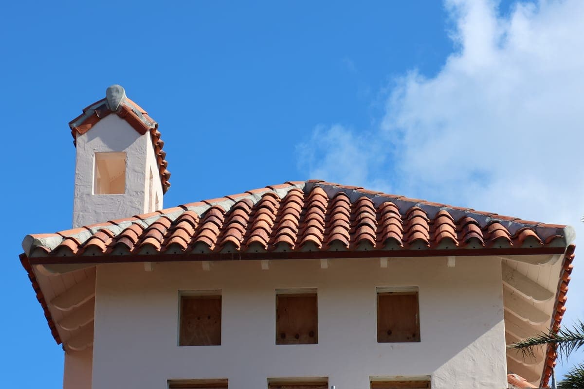White Mediterranean estate with a tile roof and chimney.