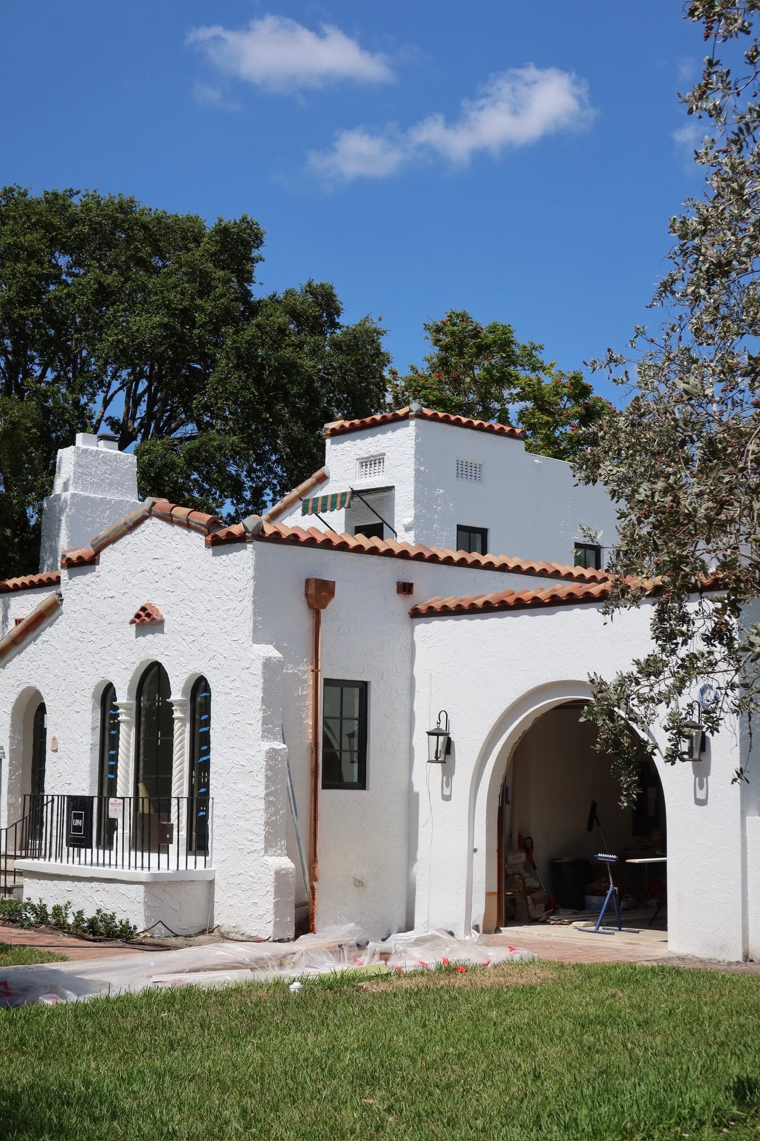 White Mediterranean home with a new barrel tile roof and arched porch.